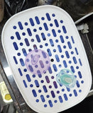 White and blue grid container with two baby pacifiers inside on a dark surface.