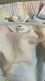 Close-up of an H&M label on a garment with a pastel tie-dye pattern.