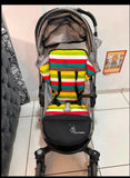 Stroller with a colorful striped seat cover on a tiled floor.