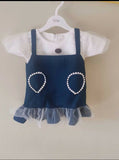 Children's outfit with navy blue dress over white shirt on a hanger against a beige background