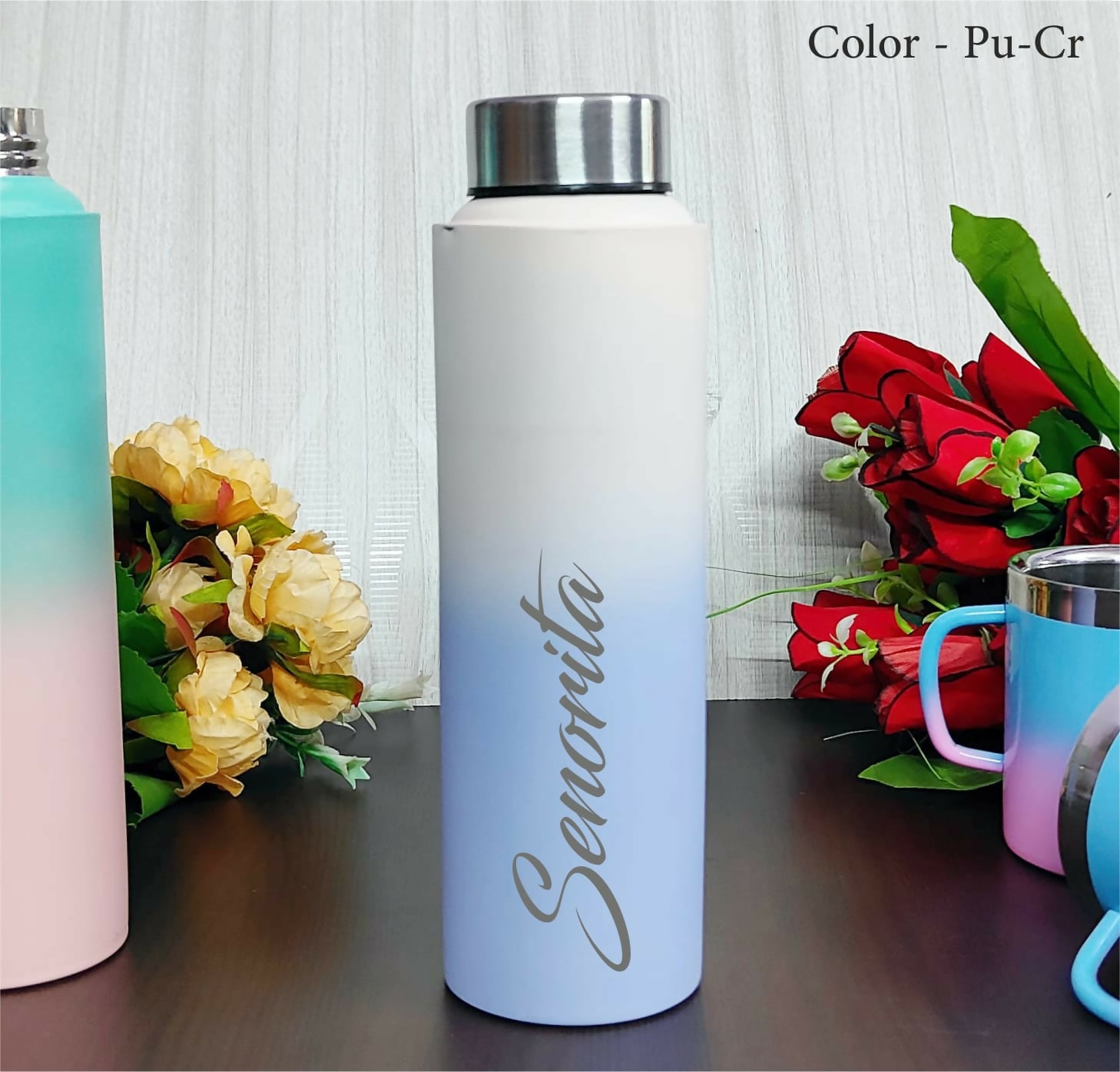 White water bottle with 'Senorita' branding on a wooden surface with flowers and other bottles.