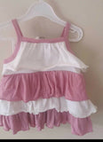 Pink and white dress on a hanger against a beige wall