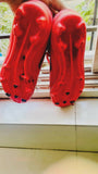 Red sandals with black heart patterns on a light-colored floor.