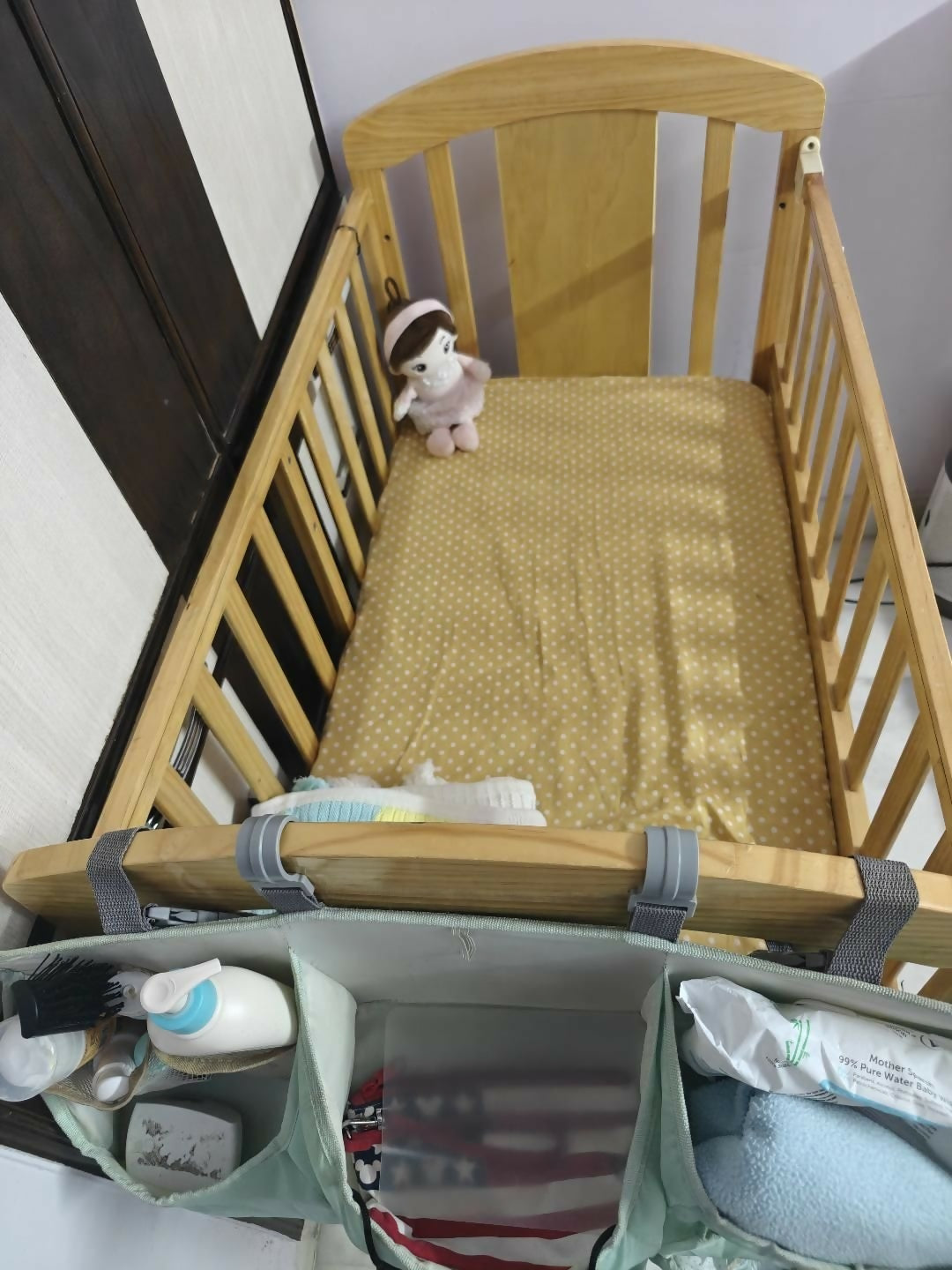 Wooden crib with a mattress and baby items on a white floor.