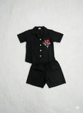 set of black short sleeved shirt and matching black shorts for a child.