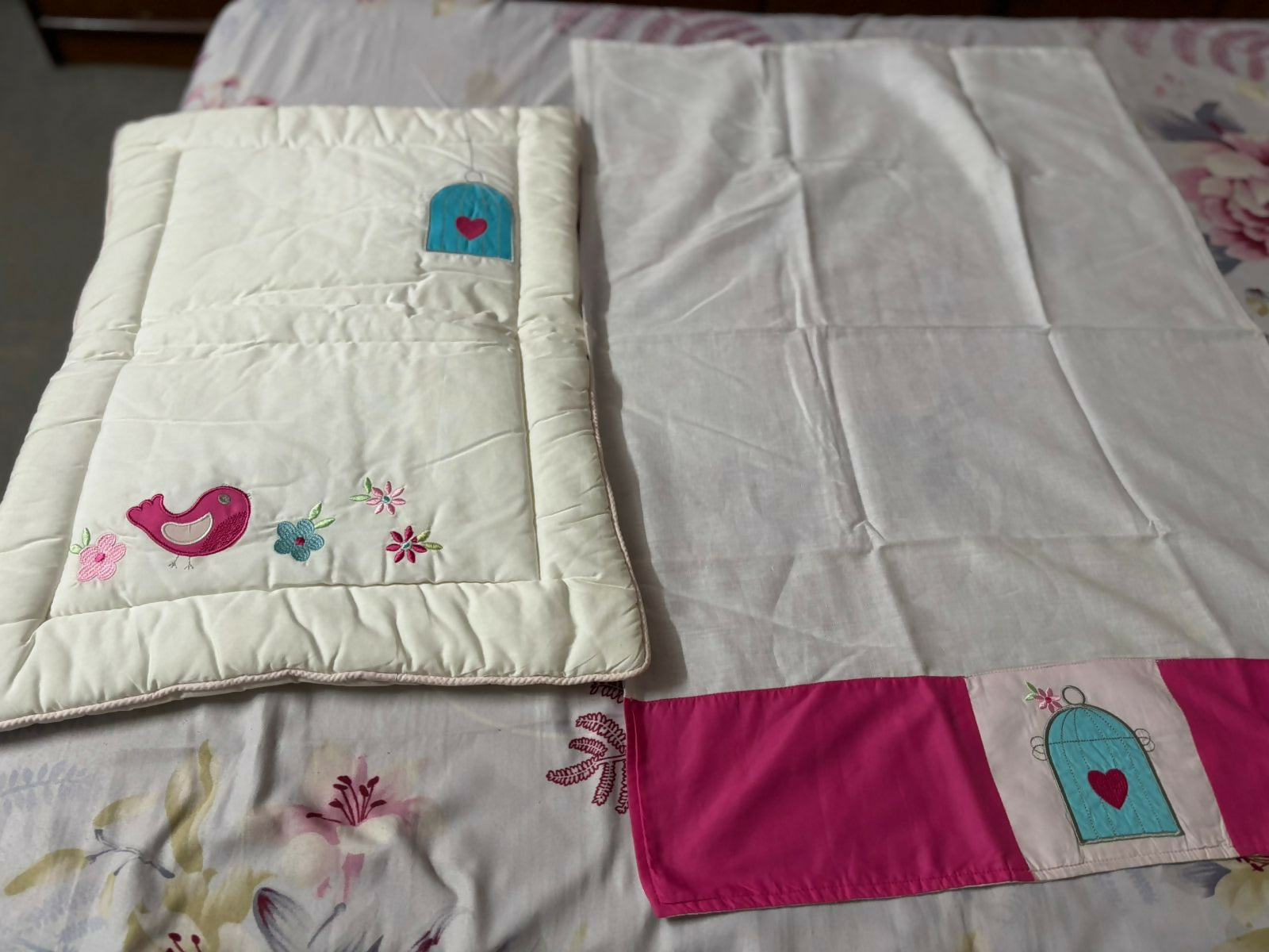 White blanket with colorful embroidery on a floral-patterned bedspread
