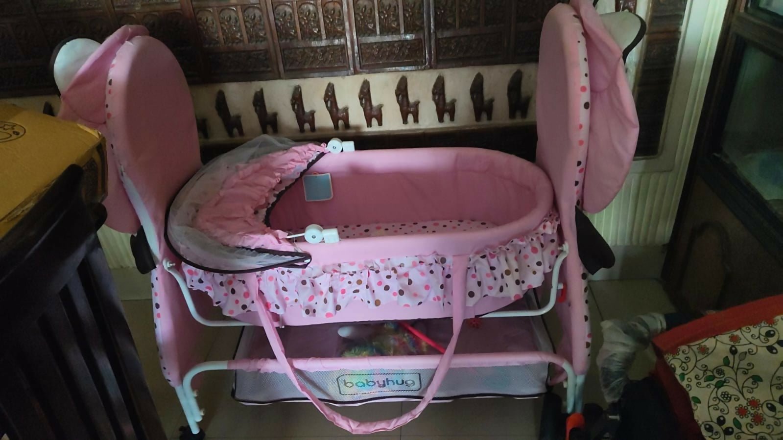 BABYHUG Froggy Print cradle with soft bedding, protective mosquito net, swing lock function, sturdy frame, and adorable frog print for a safe and comfortable sleeping space for newborns.