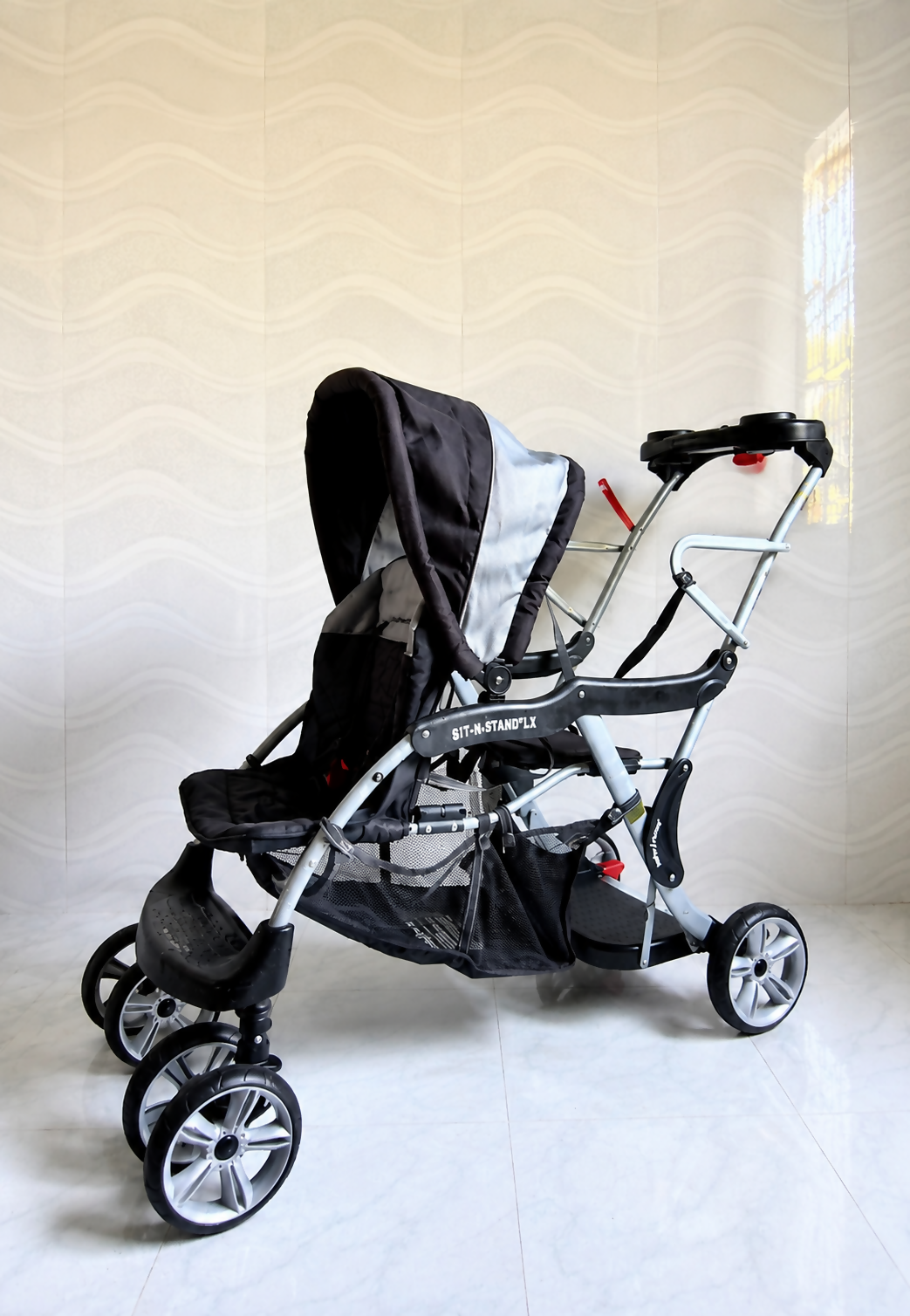 Baby Trend Sit N Stand LX double stroller tandem travel pram with front and rear seating, standing platform, safety harness, canopy, and smooth wheels for siblings.