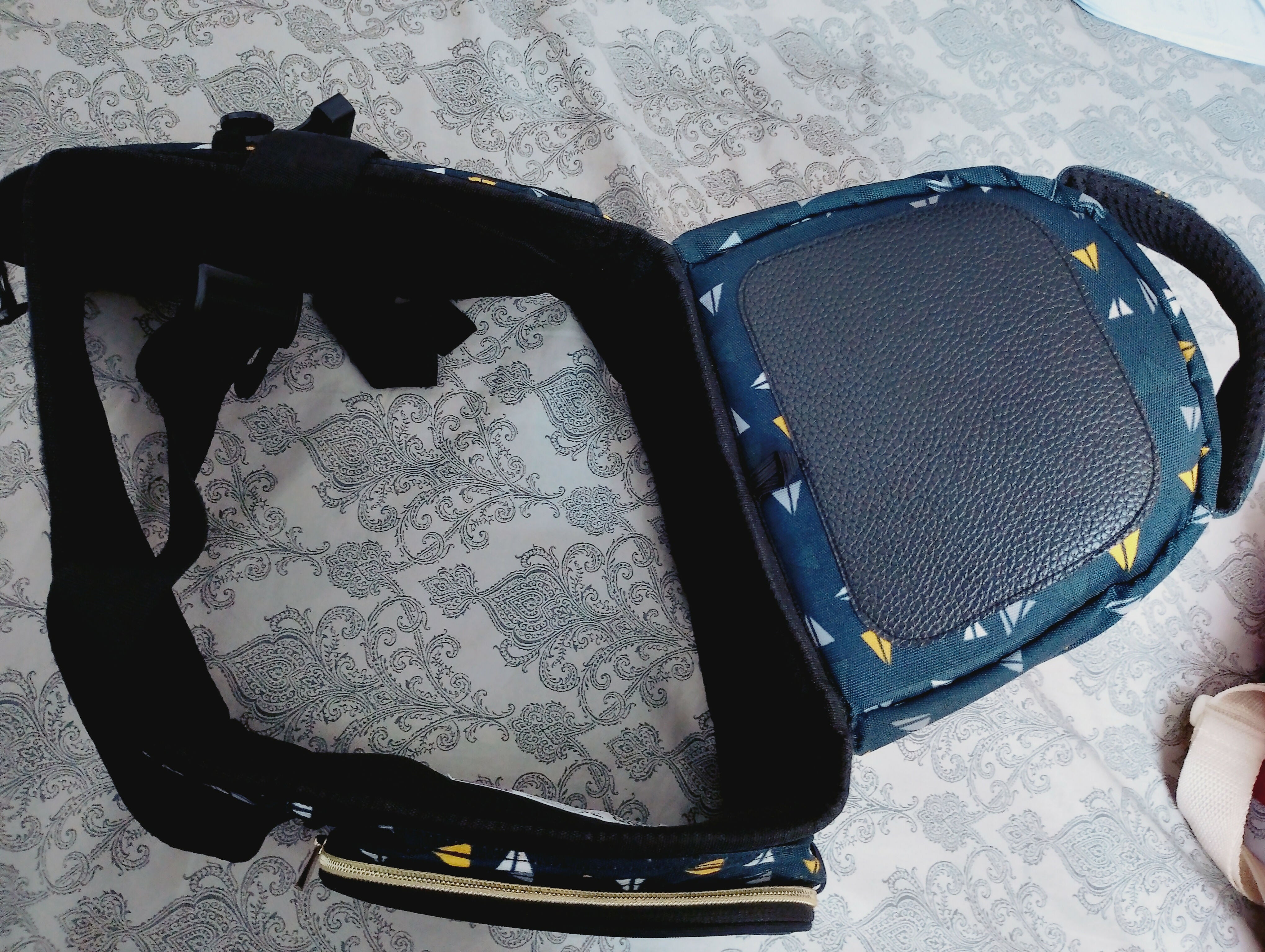 Blue baby carrier with black strap on a patterned surface