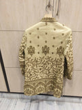 Embroidered traditional outfit on a hanger against a tiled wall.