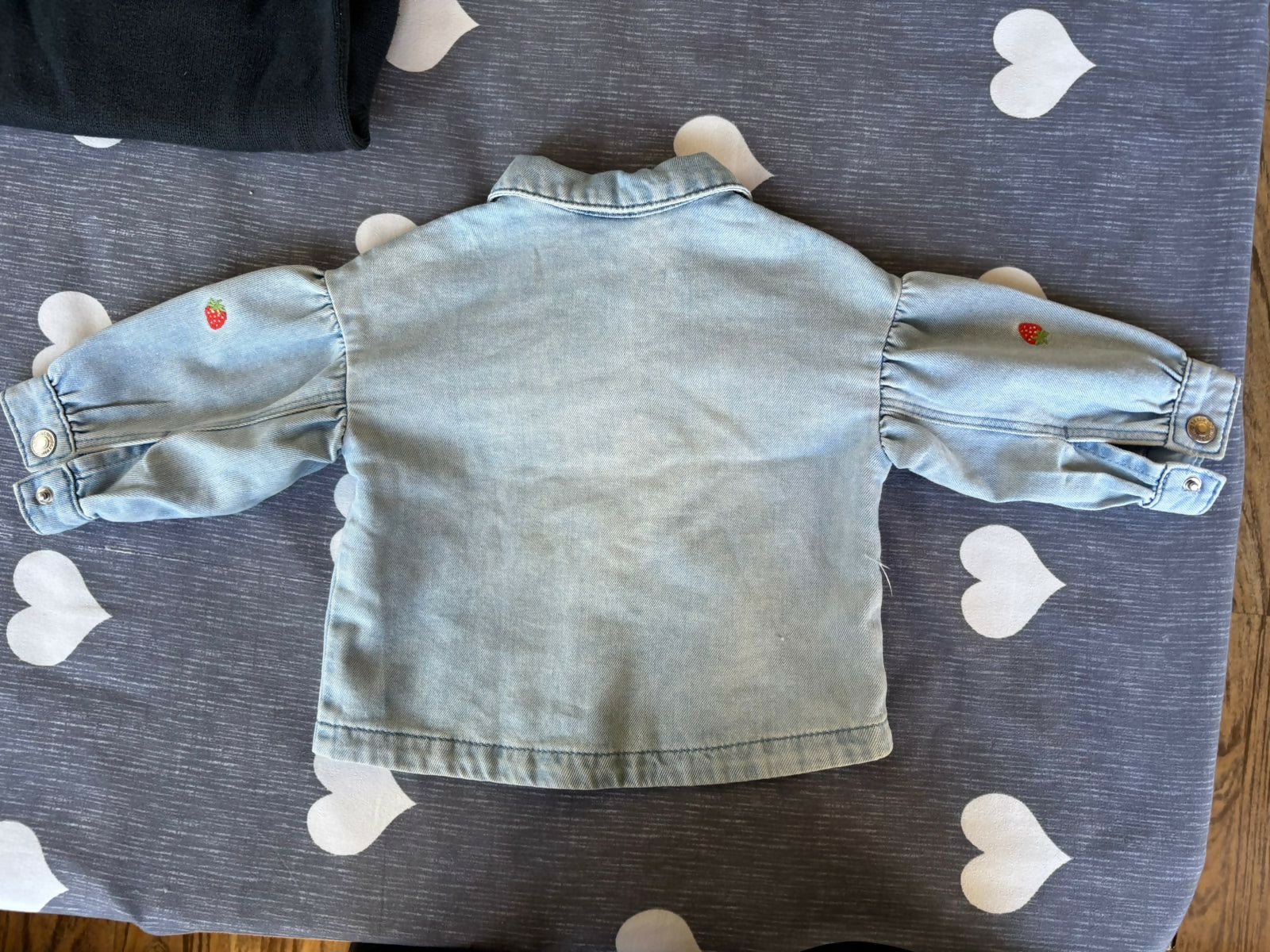 Light blue denim jacket on a gray surface with heart patterns