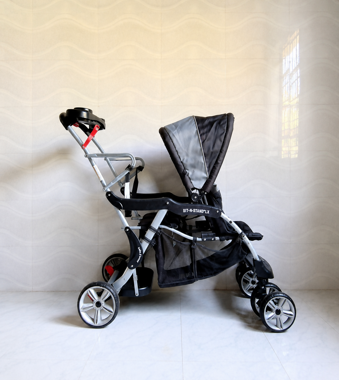 Baby Trend Sit N Stand LX double stroller tandem travel pram with front and rear seating, standing platform, safety harness, canopy, and smooth wheels for siblings.