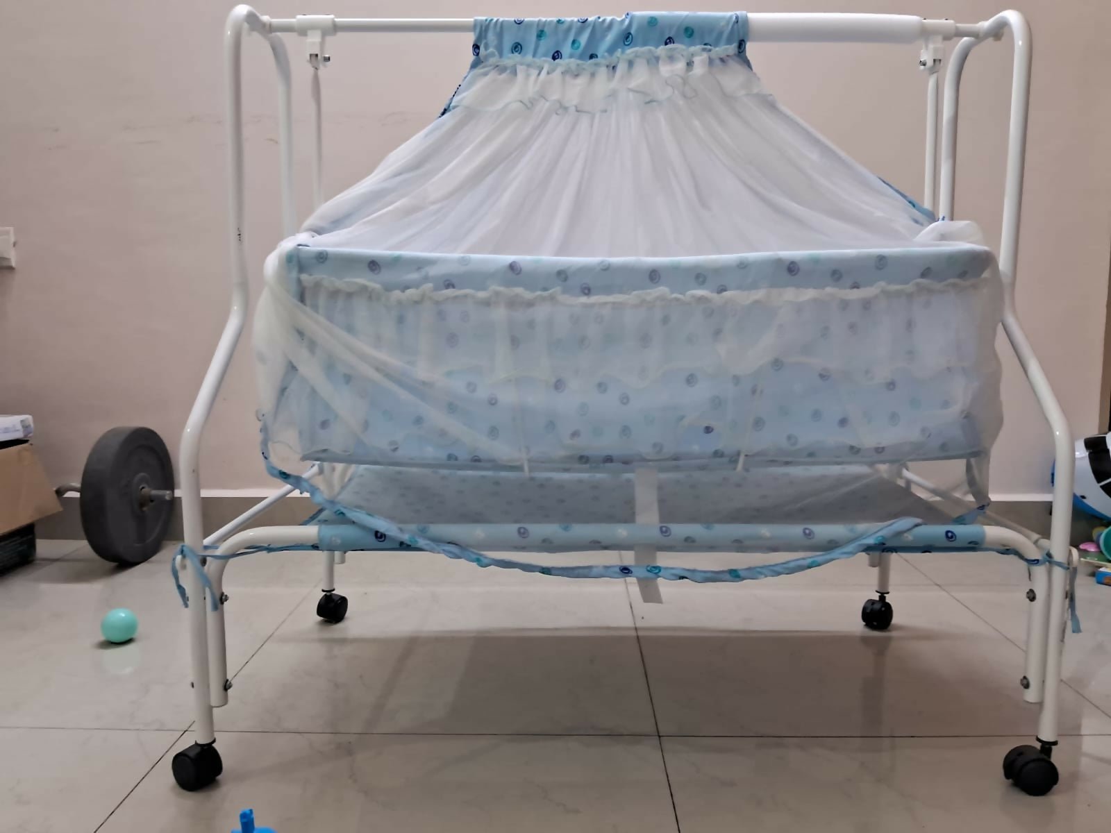 Baby crib with blue canopy on a tiled floor