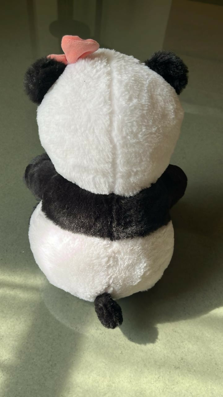 Plush panda toy with a pink bow on a light green background