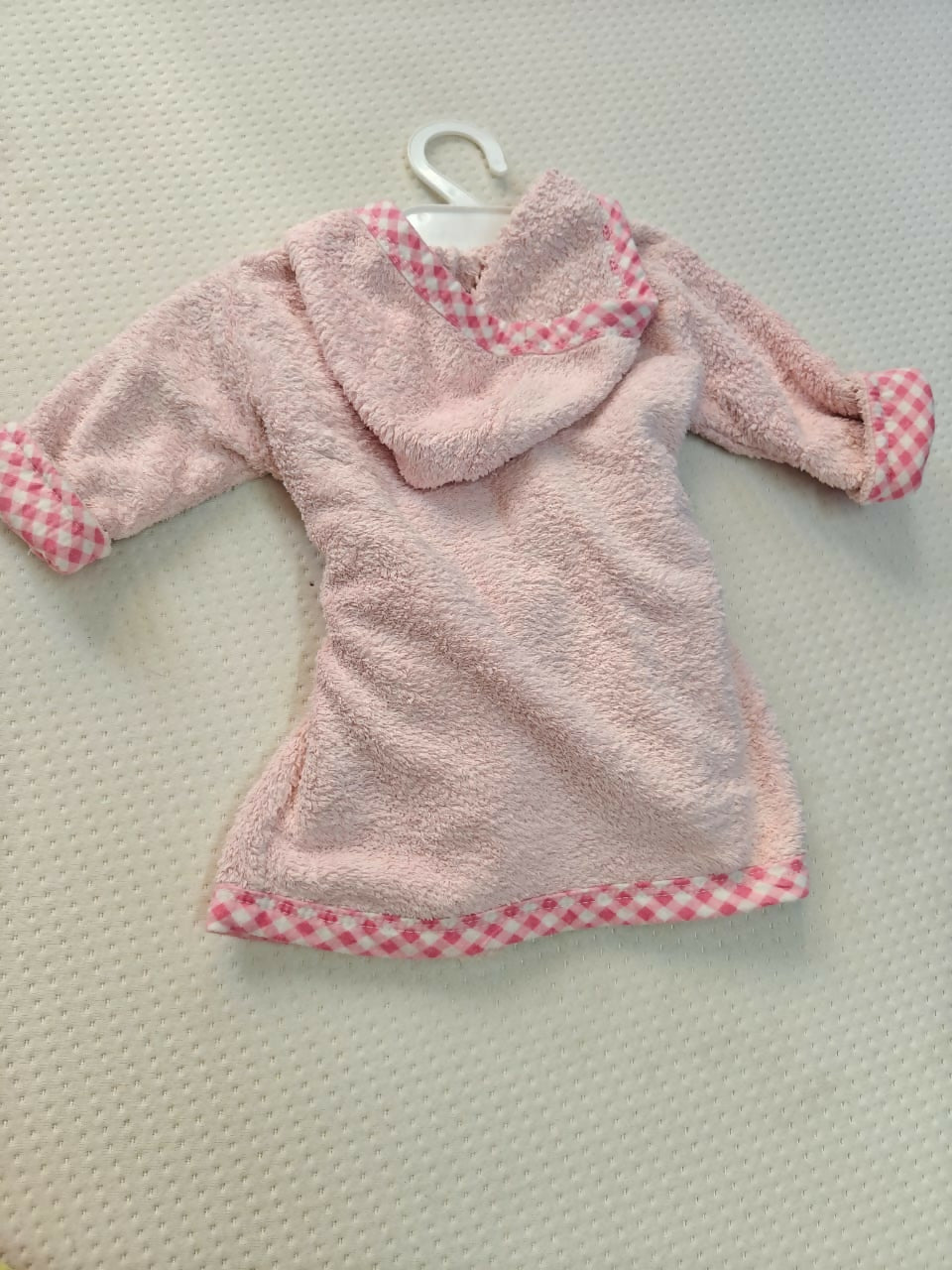 Pink children's robe with checkered trim on a hanger against a light background