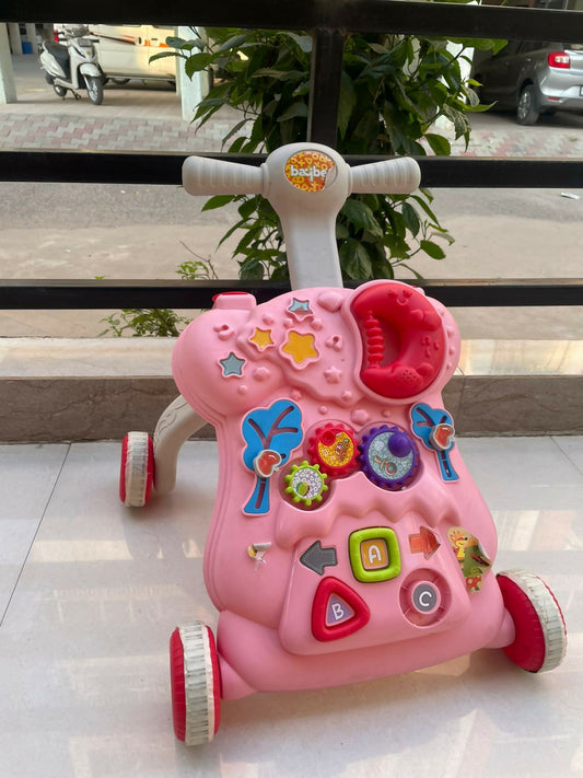 Pink toy scooter with colorful buttons on a tiled floor.