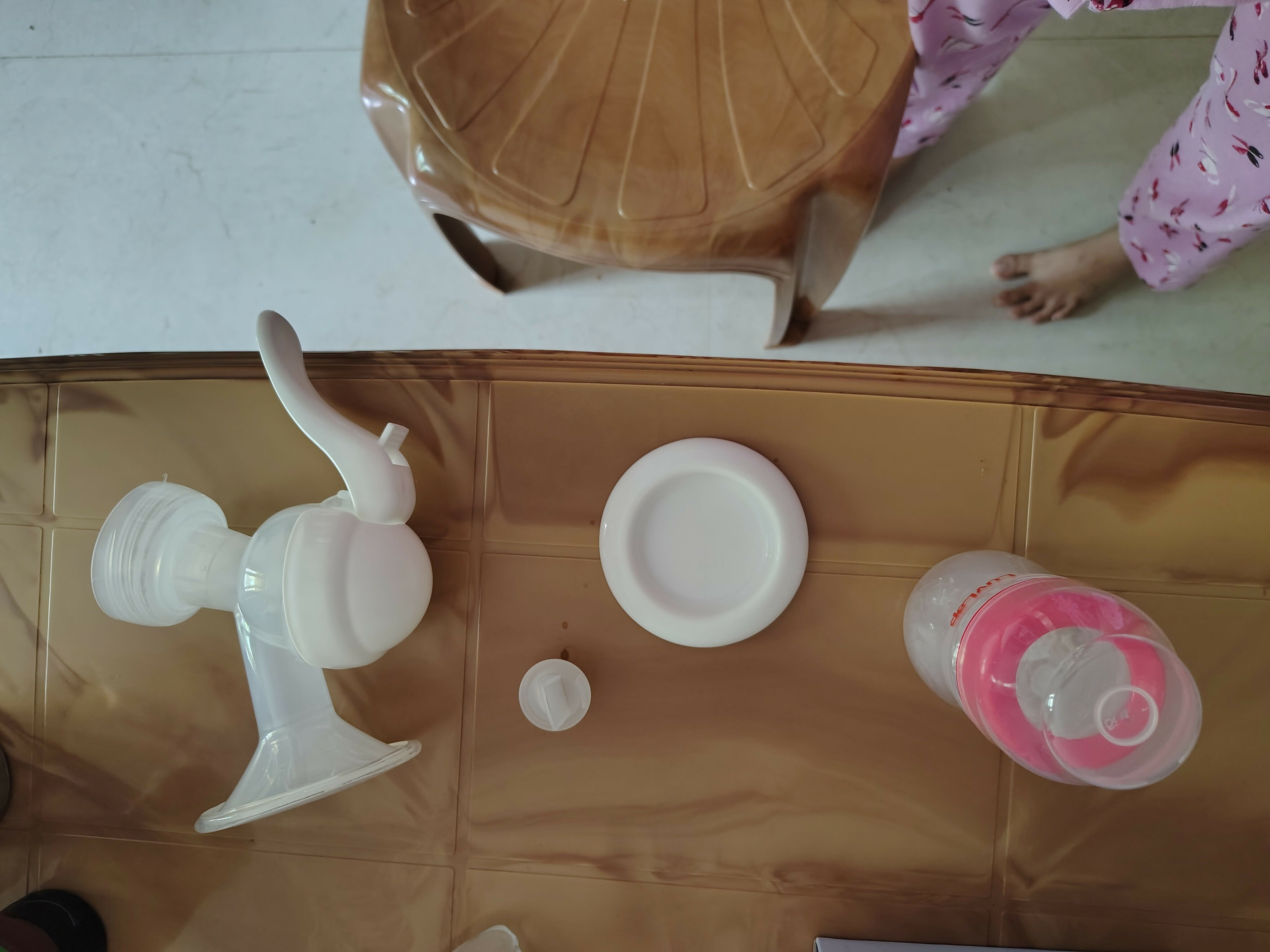 Plastic baby bottle parts on a reflective surface