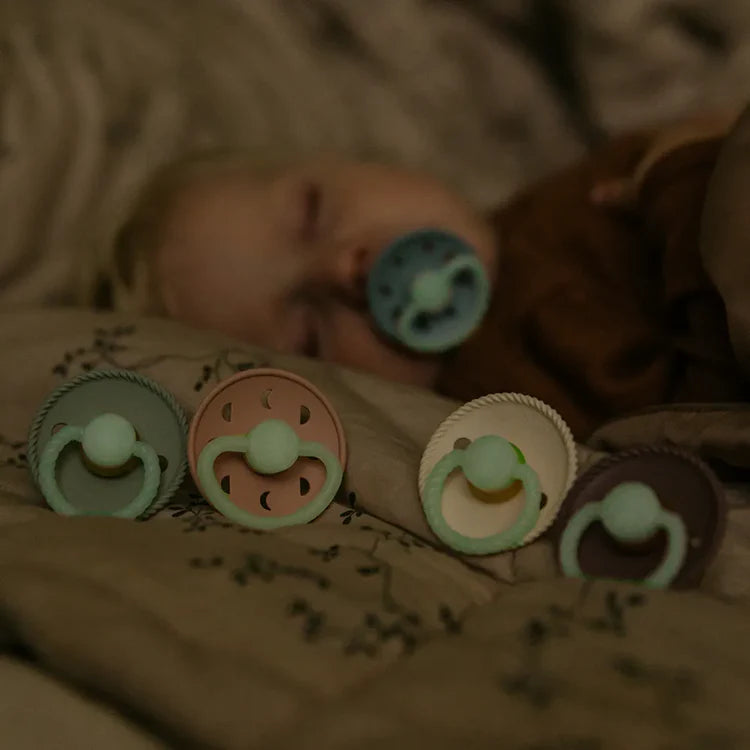 Set of colorful baby pacifiers on a soft surface with a blurred background