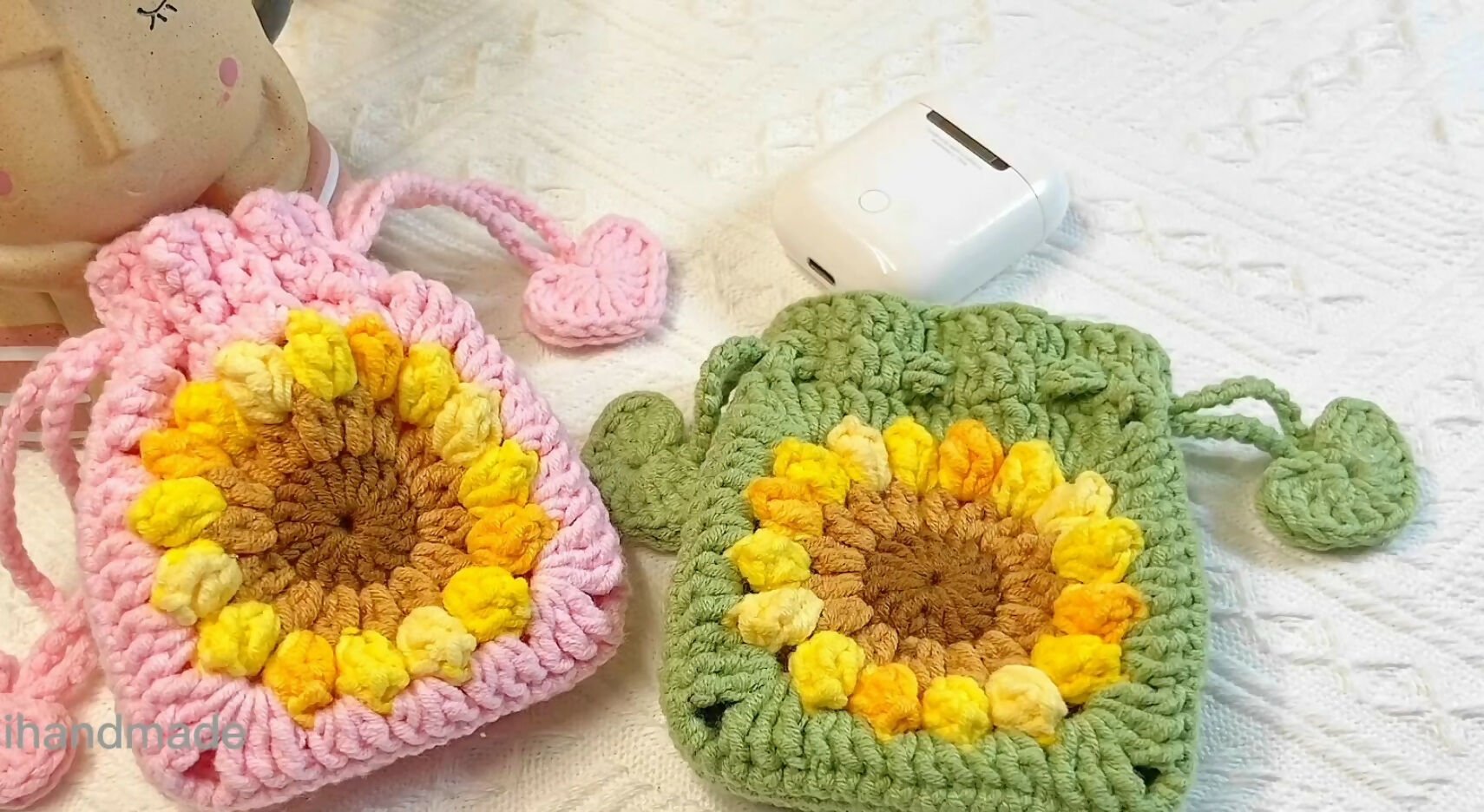 Two crocheted pouches, one pink and one green, with a sunflower pattern