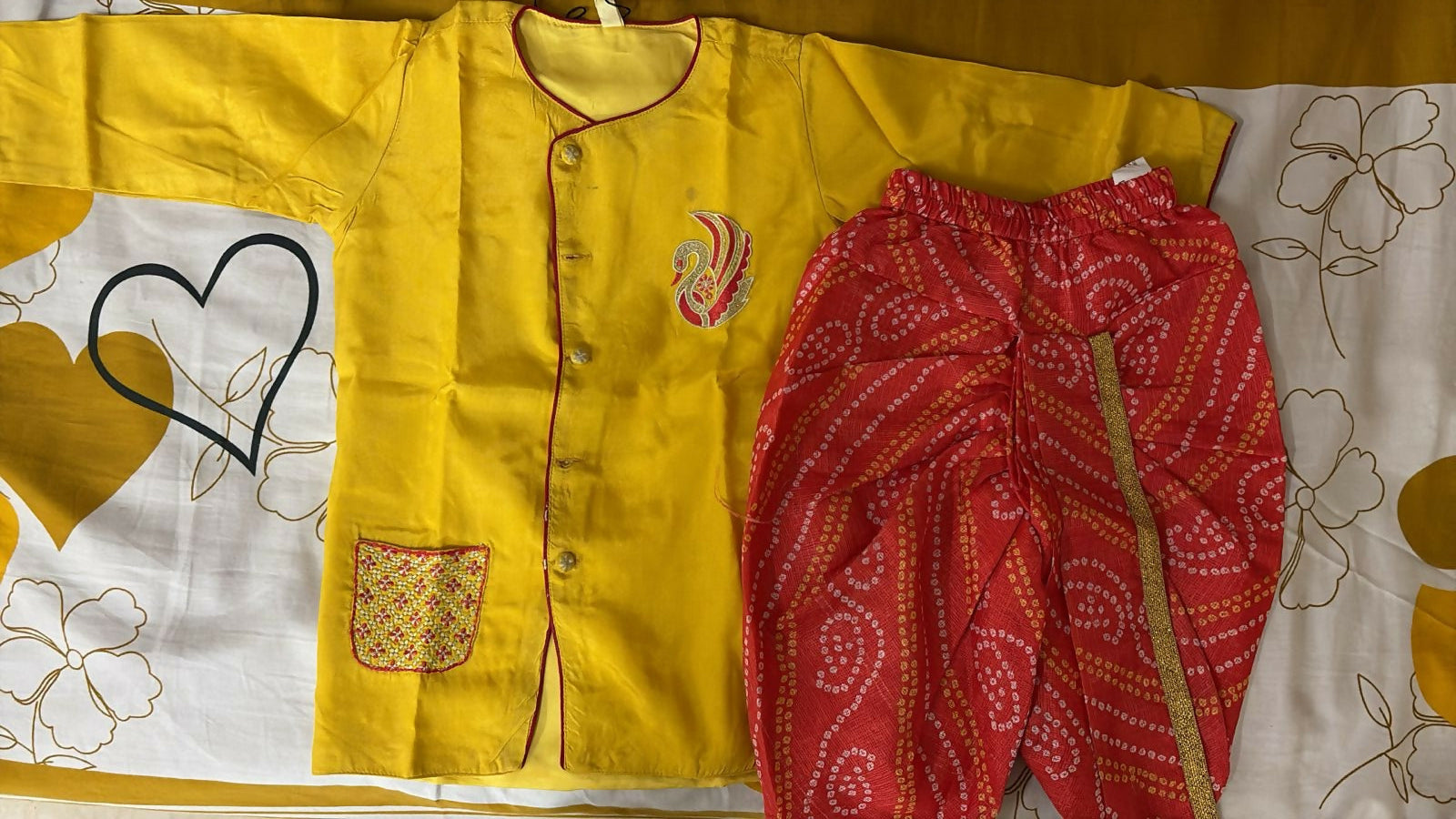 Yellow garment with floral patterns and red fabric on a yellow background