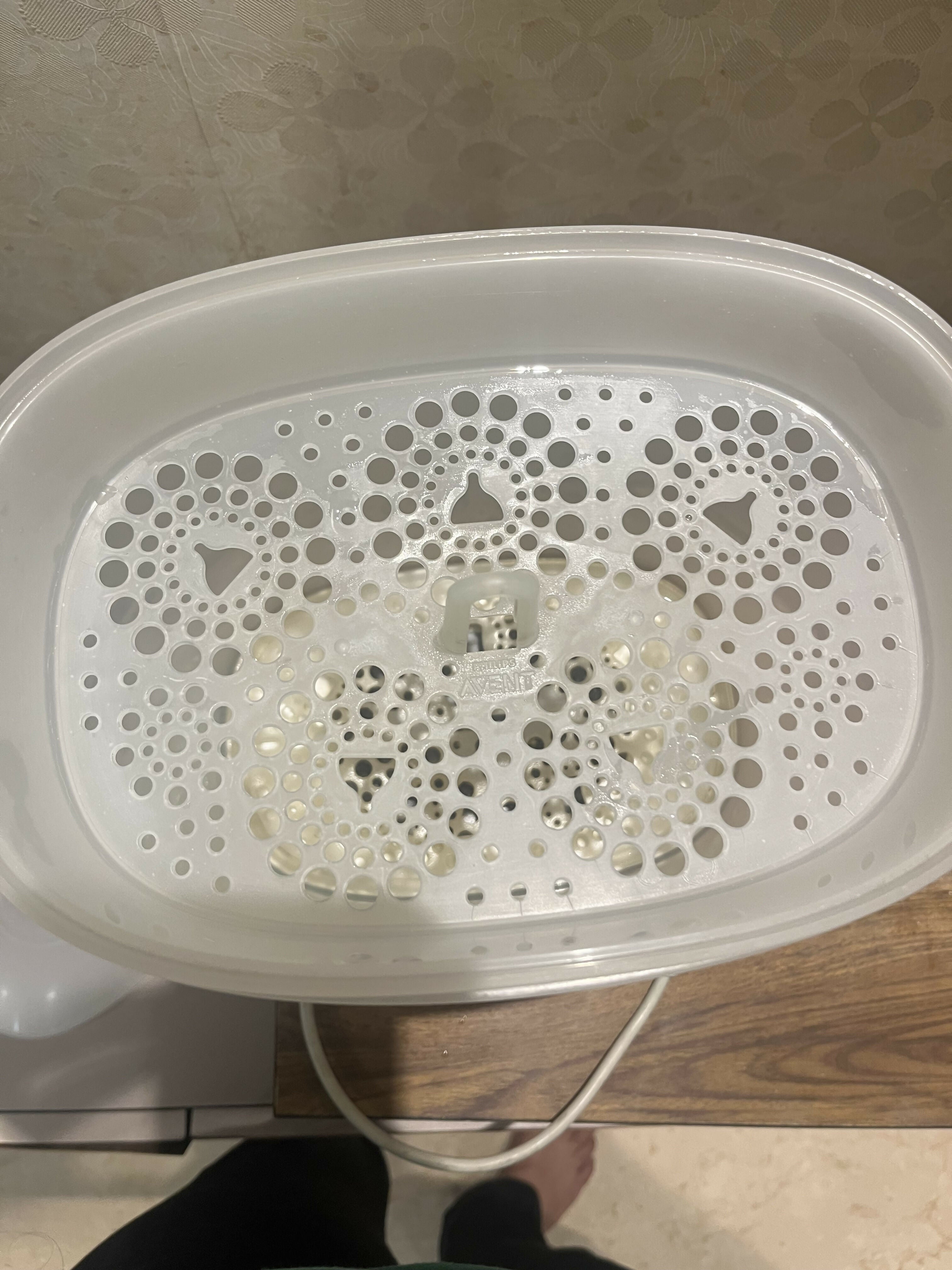 White plastic container with a lid featuring a pattern on a tiled floor.
