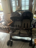 Joie and Arie twin stroller with side-by-side seating, reclining seats, adjustable canopies, 5-point safety harnesses, smooth wheels, and a foldable design for comfortable travel with twins or siblings.