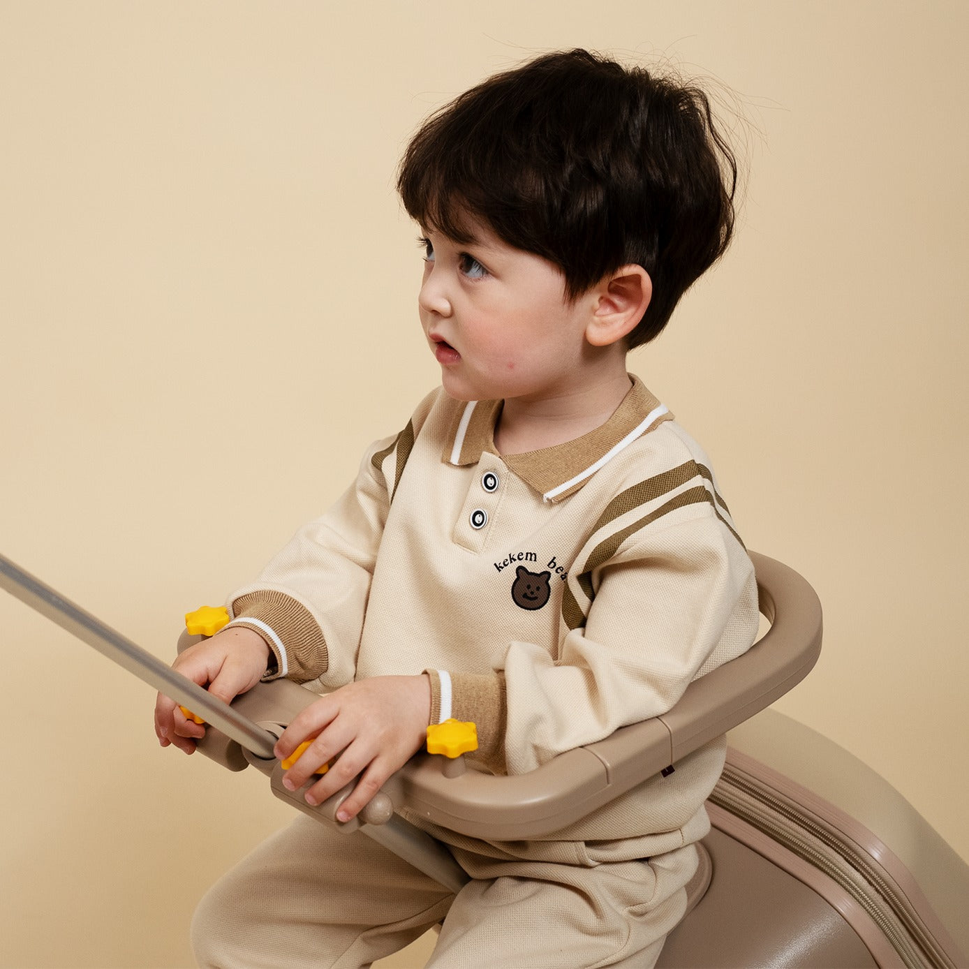 Child sitting in a beige high chair against a beige background
