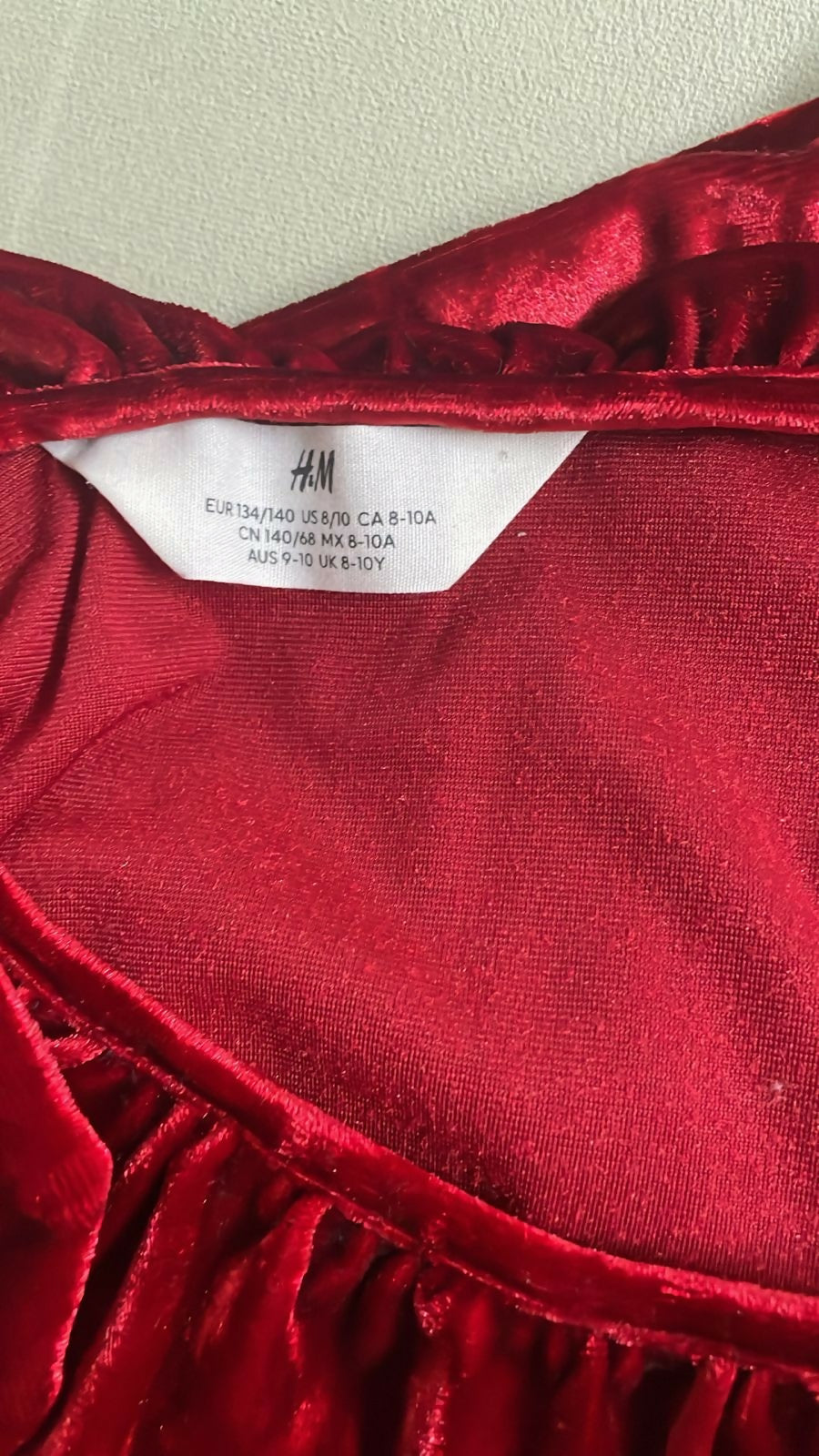 Red velvet garment with H&M label on a neutral background