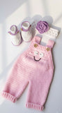 Pink knitted baby romper white booties, and purple flower