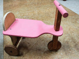 Pink wooden kids balance bike with handlebar and single front wheel, pink, brown