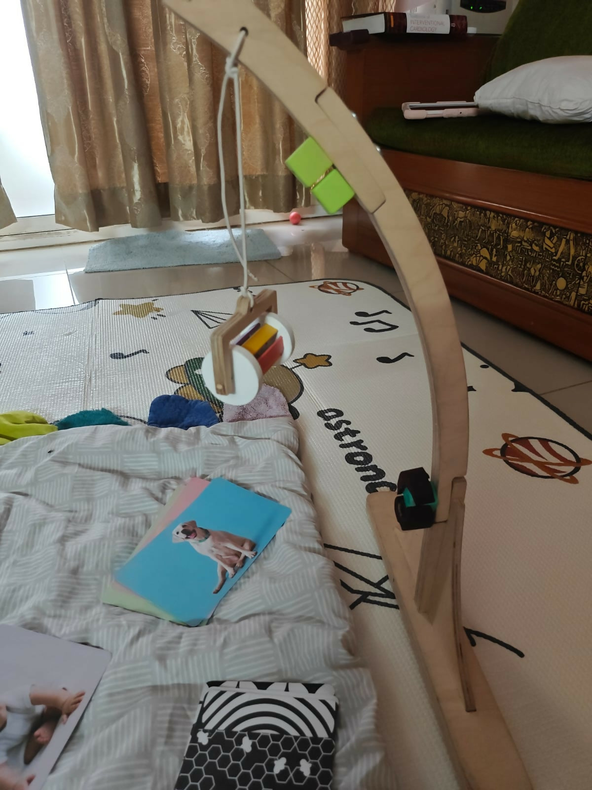 Wooden embroidery hoop on a carpeted floor with books and a curtain in the background
