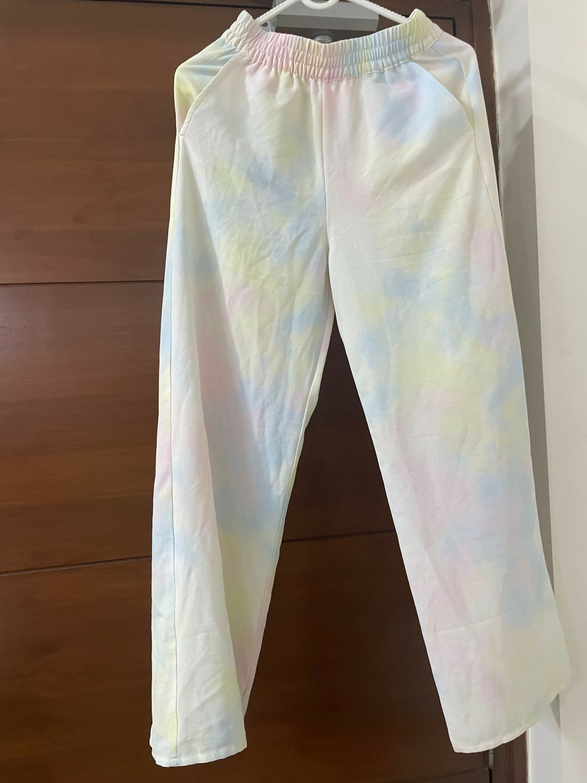 Tie-dye pants hanging against a wooden background