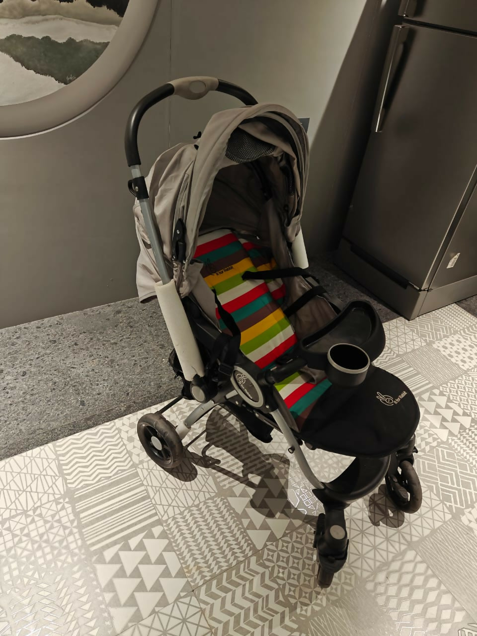 Stroller with a colorful striped blanket on a patterned floor
