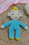 Crocheted toy with blue outfit and yellow accents on a textured surface