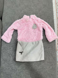 Pink fuzzy sweater and white skirt with black pattern on a gray surface
