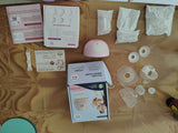 Breastfeeding supplies including a pump, bags, and instructions on a brown surface.