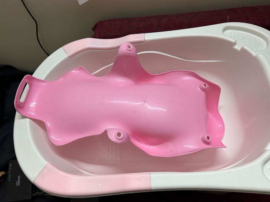 Pink baby bathtub with pink seat on a white background