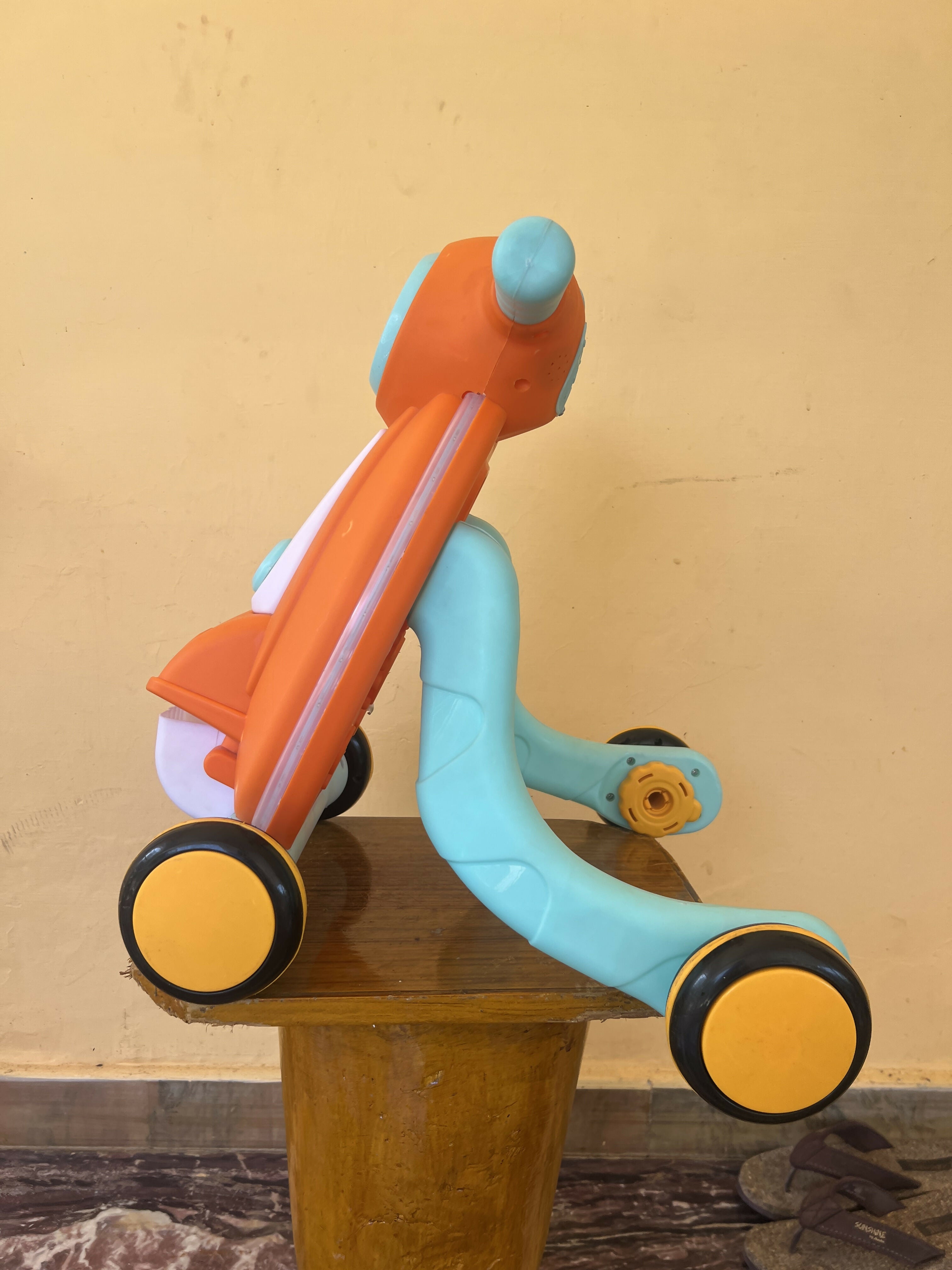 Colorful children's balance bike on a wooden surface with a yellow wall background