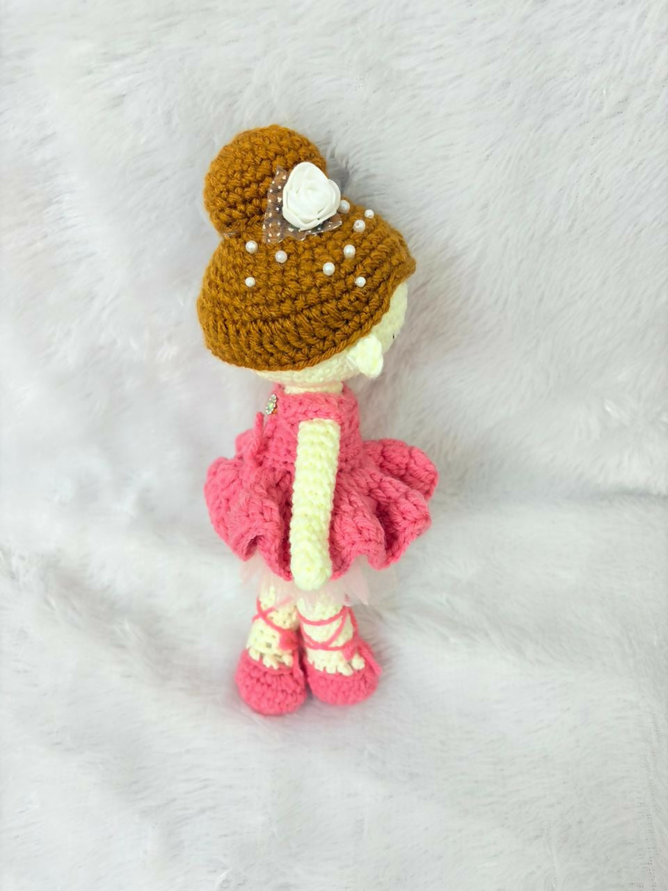 Crocheted doll with a brown hat and pink dress on a white background