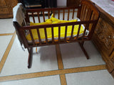 Wooden cradle with yellow mattress on a tiled floor