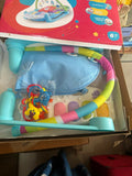 Baby play gym with colorful bars and toys on a cardboard box