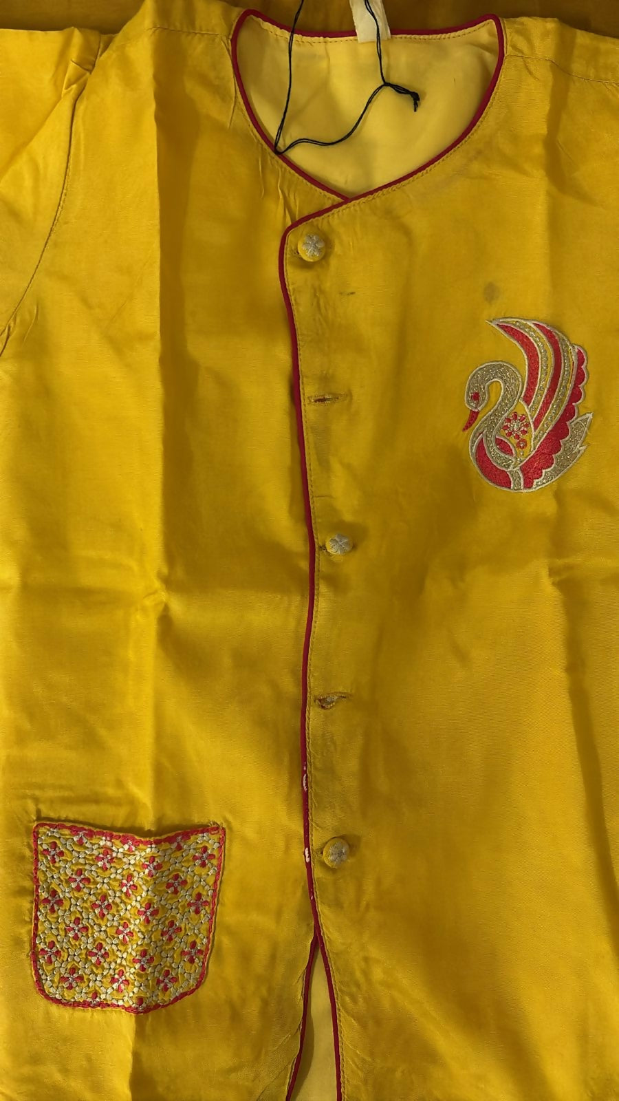 Yellow garment with a floral pocket and embroidered design on a yellow background