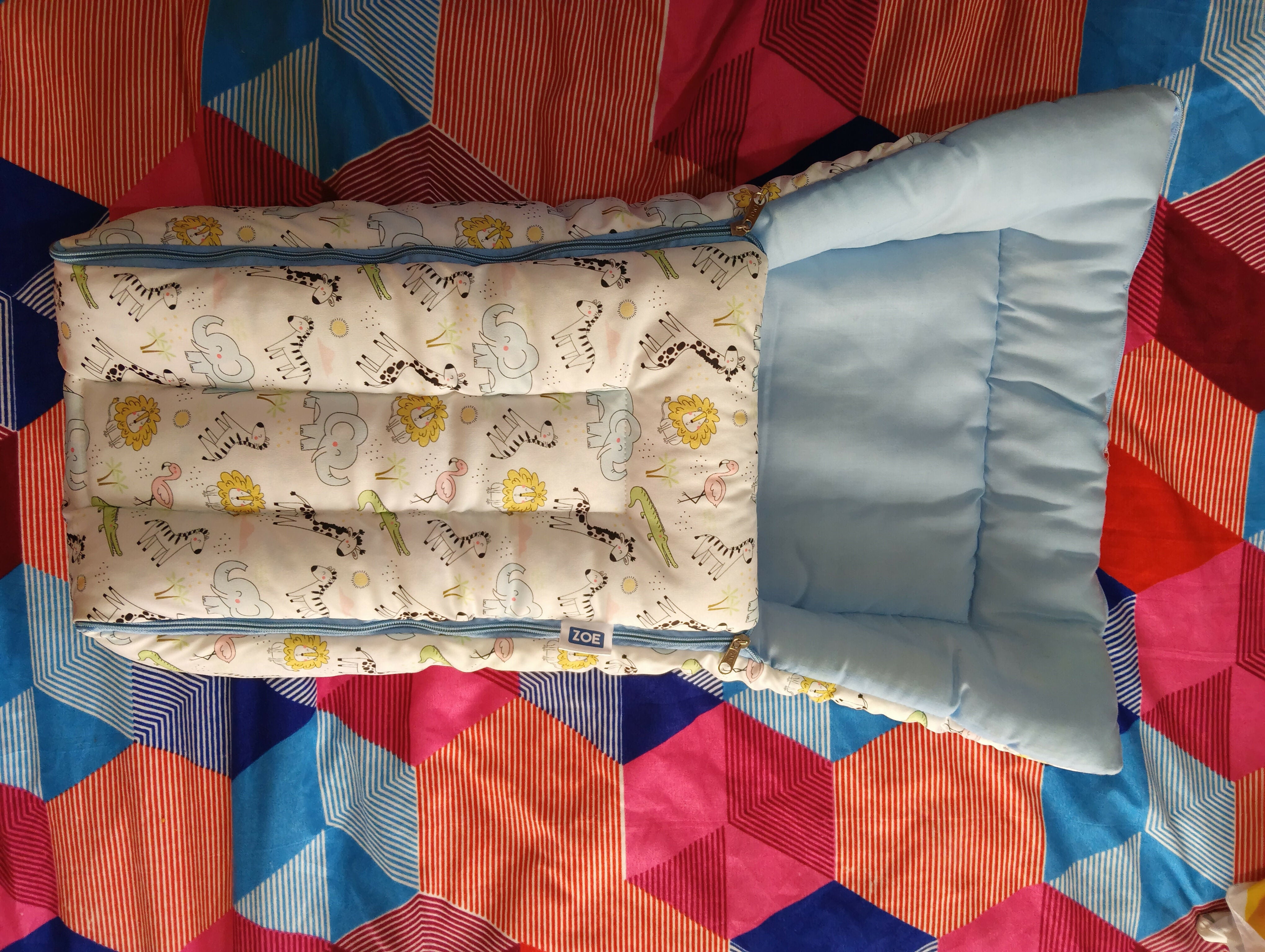 Baby crib with mattress and pillow on a colorful quilted blanket