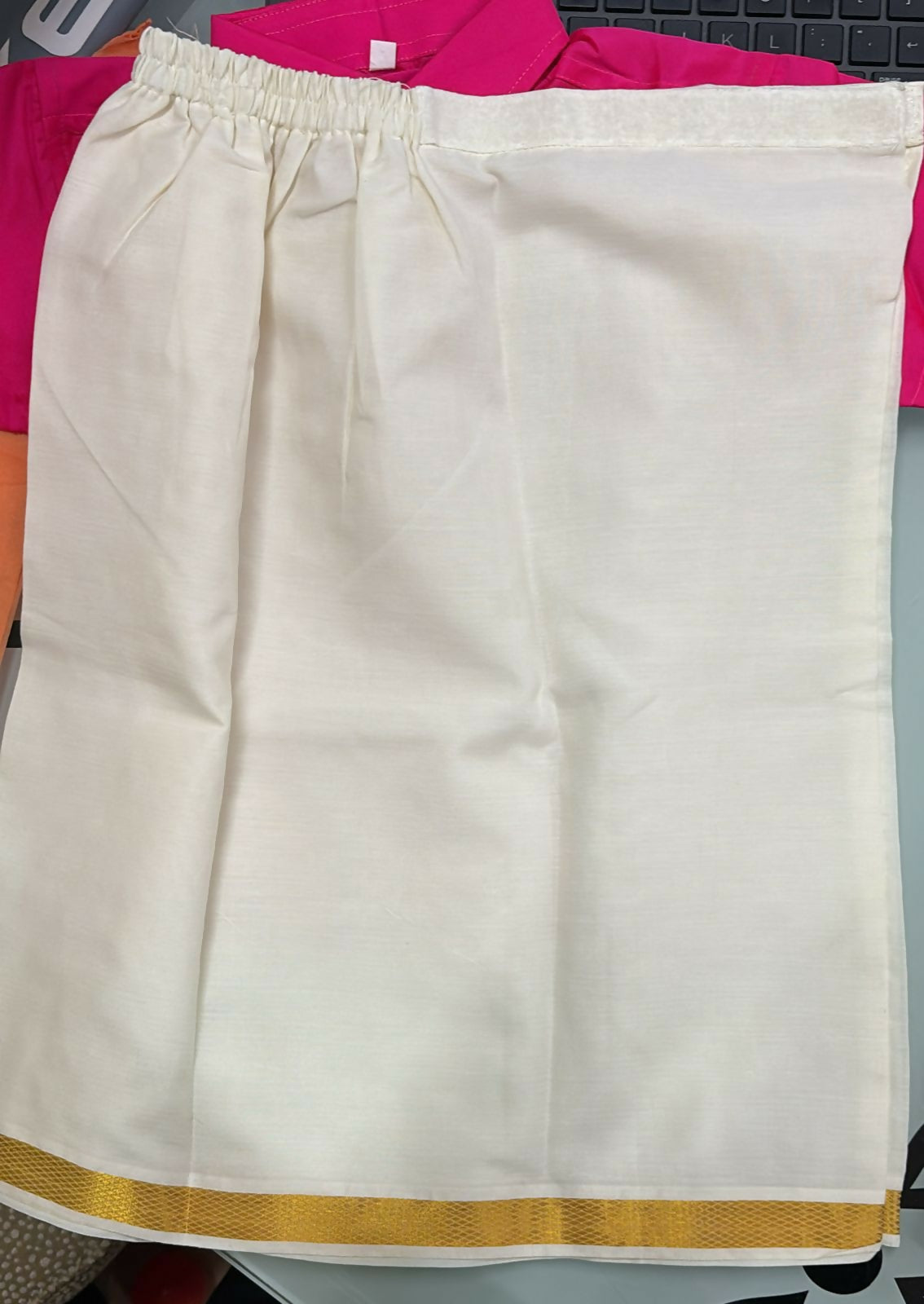 White skirt with gold trim on a pink fabric background