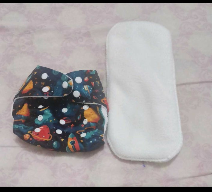 Colorful diaper with space design and white diaper cover on a light pink surface