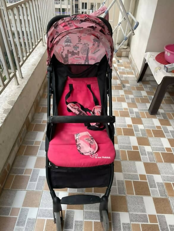 Pink and black stroller on a tiled floor