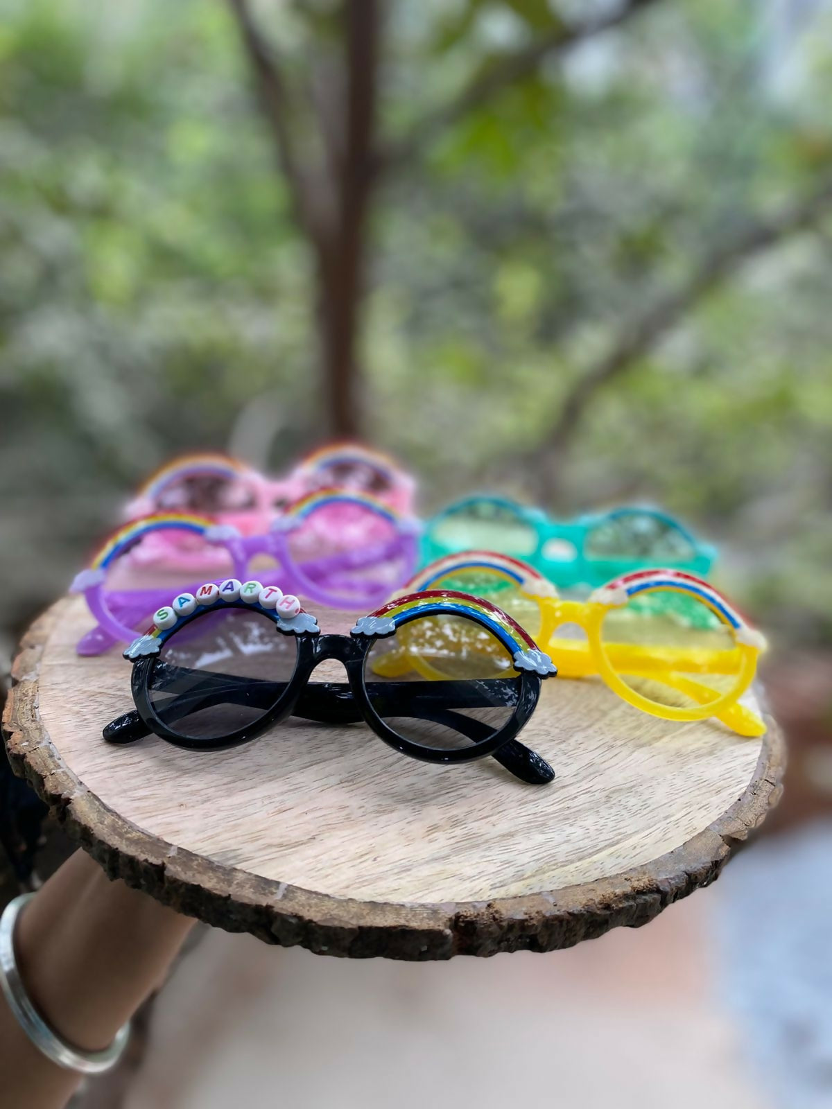 Colorful sunglasses on a wooden surface with a blurred natural background