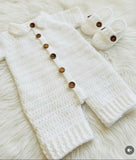 White knitted baby outfit with wooden buttons
