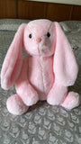 Pink plush bunny toy on a patterned surface