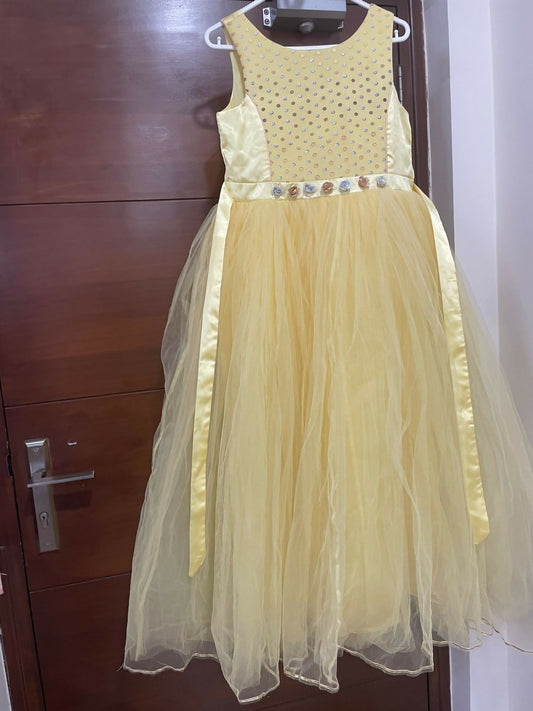 Yellow dress with floral details on a hanger against a wooden door background